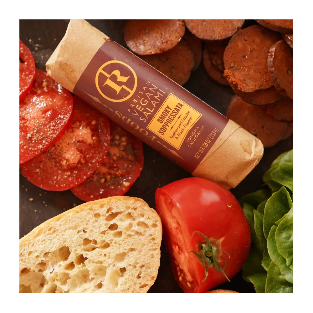 Vegan salami with bread, tomatoes, and lettuce on a dark surface