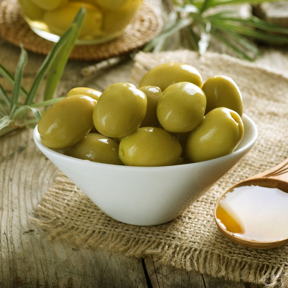 
                  
                    White Bowl of green olives on a table 
                  
                