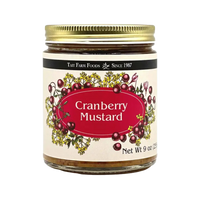 a glass jar with a red and cream label for Tait Farm Foods Cranberry Mustard